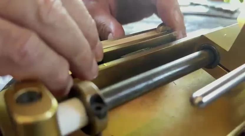 Hands placing oboe cane into the bed of a brass gouging machine